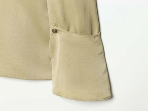 Detail of khaki blazer sleeve with layered cuff design and vintage embossed bronze button