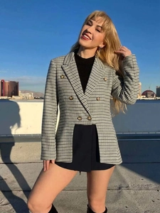 Detail of classic black and white houndstooth blazer with gold buttons against city skyline