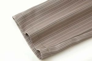 Gros plan sur la texture du tissu finement rayé et l'ourlet à couture plate soigné