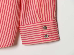Macro detail of striped poplin shirt cuff with two pearlescent grey buttons