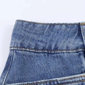 Detail of high-waist denim skirt showing blue twill texture and yellow contrast stitching