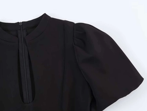 Close-up of black round neck puff sleeve dress featuring a discreet front zipper detail