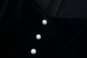 Detail of velvet dress showing three white pearl buttons and smooth fabric texture