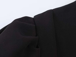 Detail shot of black dress showing puff sleeve pleat texture and fabric stitching