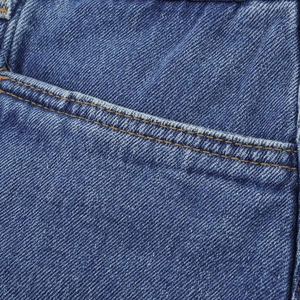 Detailed close-up of blue denim fabric showing twill texture and yellow contrast stitching