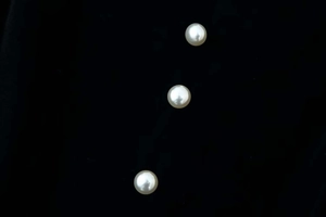Detail shot of three elegant white pearl buttons on a luxury black velvet dress fabric