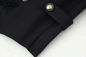 Detail of vintage bronze button and braided rope trim on a black blazer sleeve