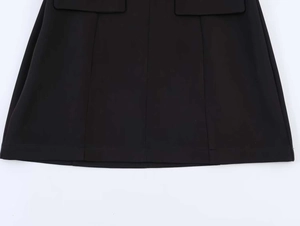 Detailed view of black mini dress featuring puff sleeves and structured seam stitching