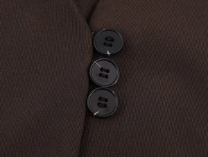 Détail macro de trois boutons noirs sur une veste sans manches marron foncé texturée