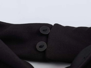 Macro detail of high-quality black knit fabric with two circular button closures on dress