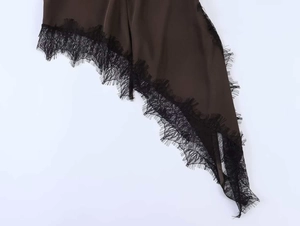 Détail macro de l'ourlet asymétrique en satin marron avec bordure en dentelle noire