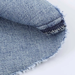 High-waist pleated denim skirt in vintage blue with frayed edges and twill texture