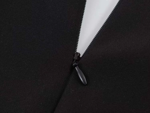 Detailed close-up of a concealed back zipper on a black puff sleeve dress