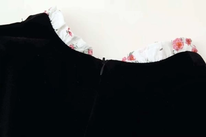 Close-up of black velvet dress featuring pink floral ruffles and a seamless invisible zipper