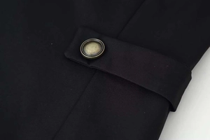 Detailed macro view of vintage bronze metal button and shoulder strap on black blazer