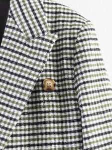 Detail of green plaid blazer showing tweed texture and amber button closeup