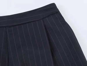 Detailed view of navy blue pinstripe suit trousers with visible pocket and waistband stitching