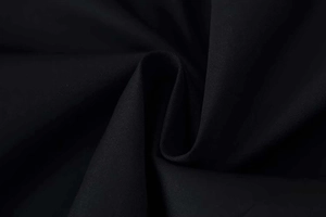 Close-up of black blazer fabric showing fine twill texture and structured padded shoulder