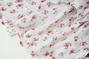 Close-up of pink rose floral print on white chiffon fabric with vertical texture