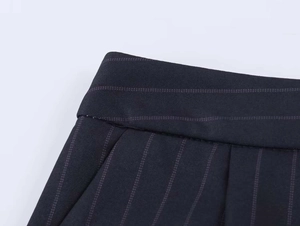 Detailed close-up of dark pinstripe suit waist featuring precise double stitching