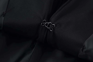 Macro detail of the metal hook-and-eye closure on a high-density black twill blazer
