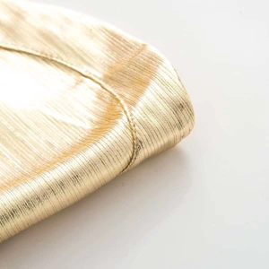Detail shot of shimmering gold metallic bandage fabric with fine pleated texture and stitching