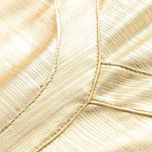 Detailed macro view of the gold metallic fabric and professional double stitching on the dress