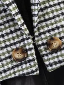Macro detail of plaid blazer featuring green houndstooth wool fabric and tortoise buttons