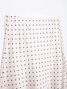 Dettaglio della gonna midi in raso beige con motivo minimalista a pois neri