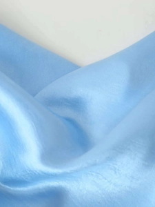 Détail du tissu satiné bleu clair avec texture soyeuse élégante et drapé fluide
