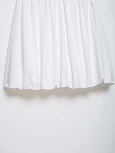 Detailed close-up of a white midi skirt featuring vertical pleats and bubble hem design