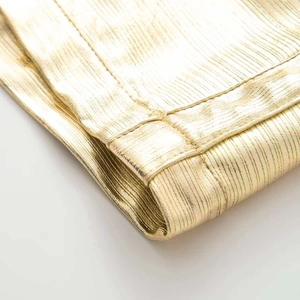 Detail shot of golden metallic fabric showing fine pleats and high-quality hem stitching