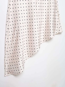 Dettaglio gonna in raso a pois con orlo asimmetrico e tessuto beige chiaro lucido