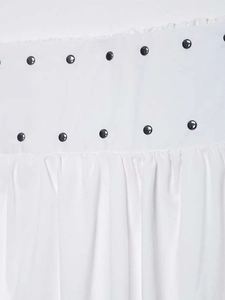 Detail of white midi skirt featuring pleated fabric and decorative black metal studs