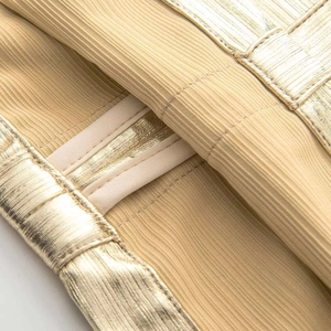 Macro shot of gold metallic ribbed fabric with high shine finish and premium double stitching