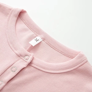 Detailaufnahme des rosa gerippten Babybodys mit silbernen Druckknöpfen und Größenetikett M