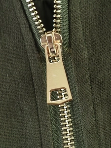 Macro detail of high-quality gold metal zipper on dark green knitted bomber jacket