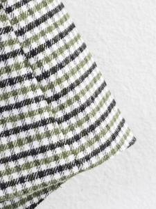 Close-up detail of green and black tweed fabric texture with intricate woven patterns