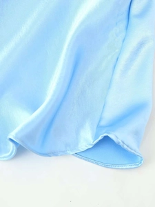 Détail de l'ourlet de la robe en satin bleu ciel montrant le tissu lisse et les coutures