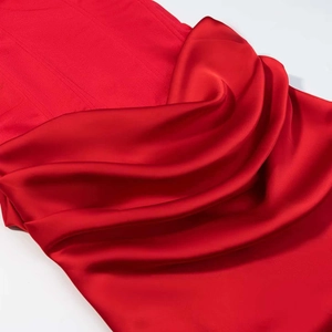 Gros plan détaillé sur les textures de satin rouge et de maille côtelée d'une robe
