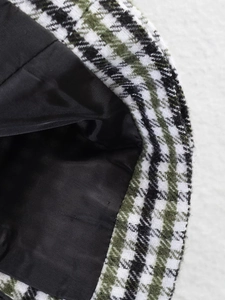 Macro detail of houndstooth plaid fabric texture and smooth black satin lining on the hat