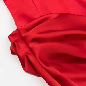 Détail de tissu en satin rouge luxueux montrant une texture lisse et des plis drapés