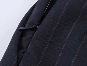 Detailed close-up of high-quality concealed zipper on black pinstripe fabric garments