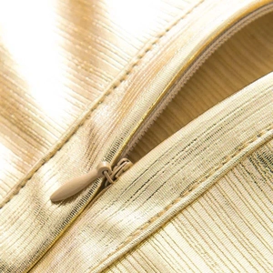 Close-up of golden metallic bandage dress fabric with texture and invisible zipper detail