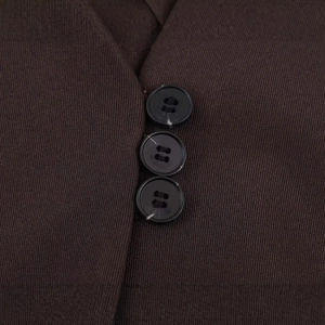 Gros plan du gilet marron foncé avec tissu texturé et trois boutons noirs alignés