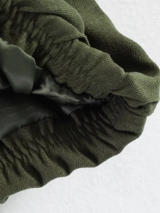 Detail of olive green elastic waistband with fabric texture and smooth satin lining