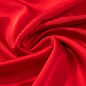 Détail du tissu en satin rouge avec texture lisse et élégant drapé plissé sur robe d'été