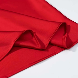 Détail du tissu en satin rouge montrant la texture lisse et les coutures de l'ourlet