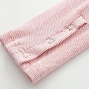 Nahaufnahme von rosa geripptem Jumpsuit mit robusten silbernen Metalldruckknöpfen