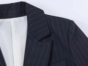 Detail view of peak lapels and fine vertical pinstripes on navy blue blazer fabric